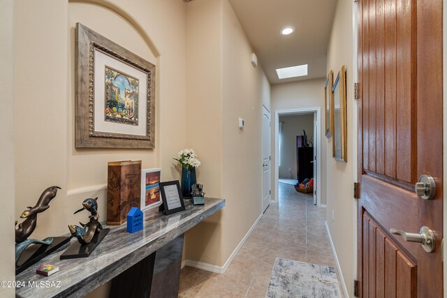 hall with baseboards, recessed lighting, light tile patterned floors, and a skylight