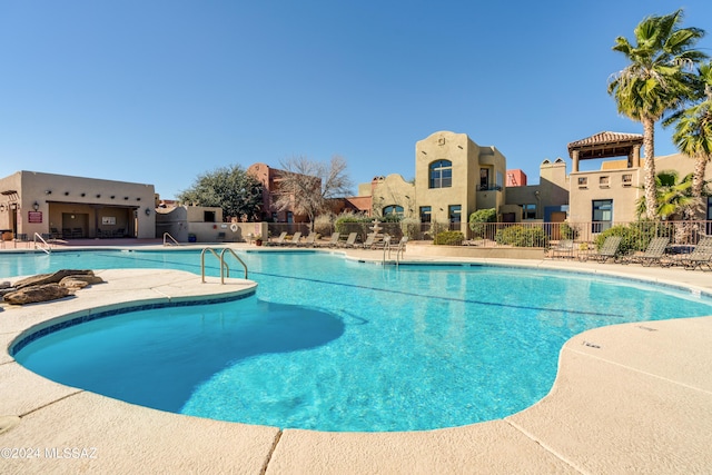 community pool with a patio and fence