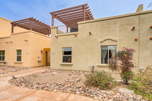 exterior space featuring stucco siding and a pergola
