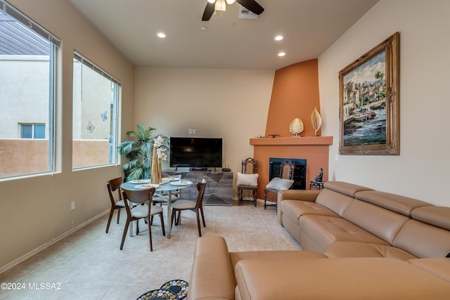 living room featuring a large fireplace, ceiling fan, and light tile patterned floors