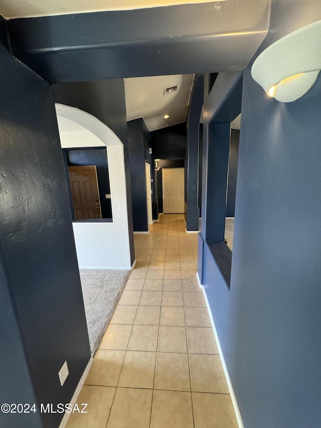 corridor with light tile patterned floors and lofted ceiling