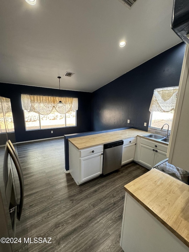 kitchen with stainless steel dishwasher, dark hardwood / wood-style flooring, hanging light fixtures, white cabinets, and butcher block counters