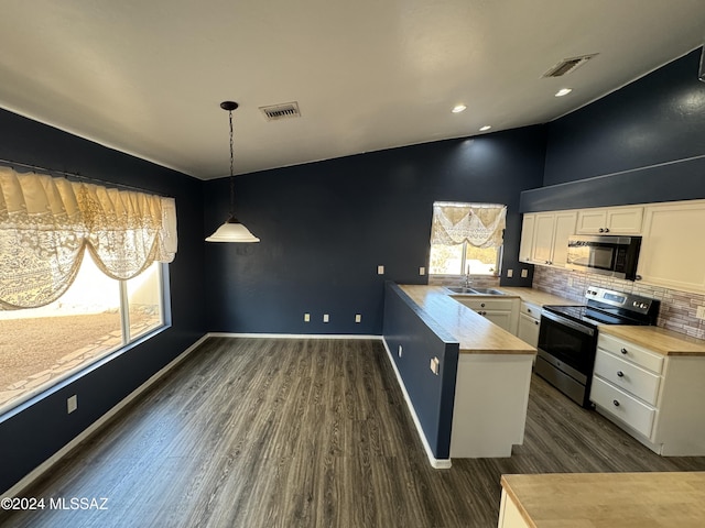 kitchen with kitchen peninsula, appliances with stainless steel finishes, pendant lighting, white cabinets, and sink