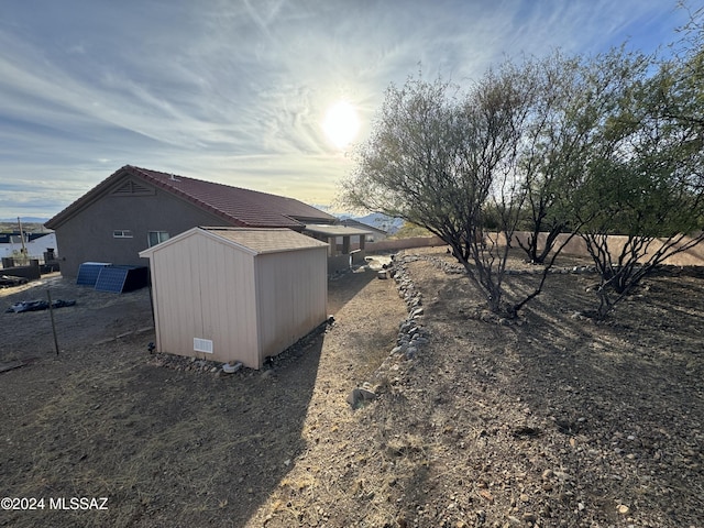 property exterior at dusk with a storage shed and solar panels