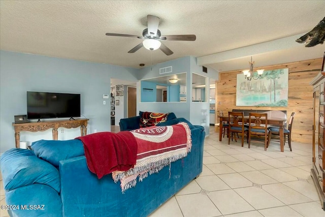 tiled living room with ceiling fan with notable chandelier, wood walls, and a textured ceiling