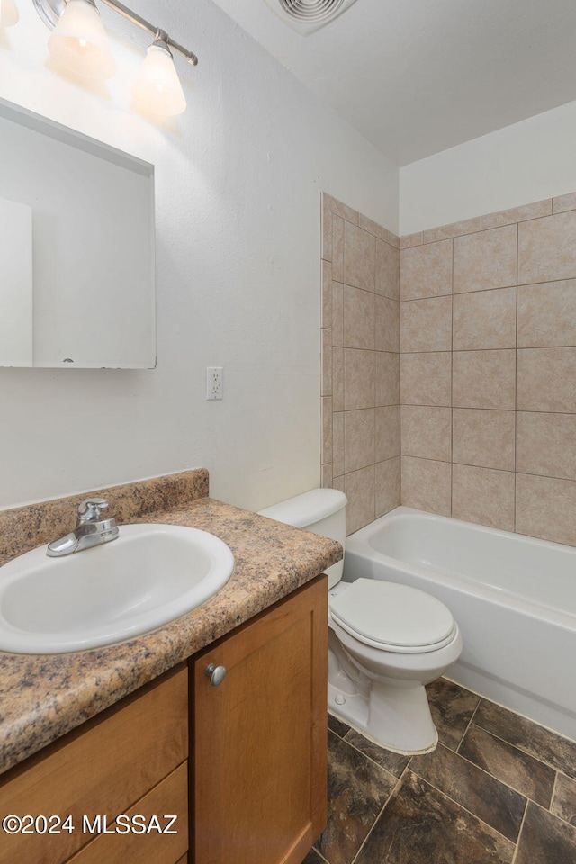 full bathroom with tiled shower / bath, vanity, and toilet