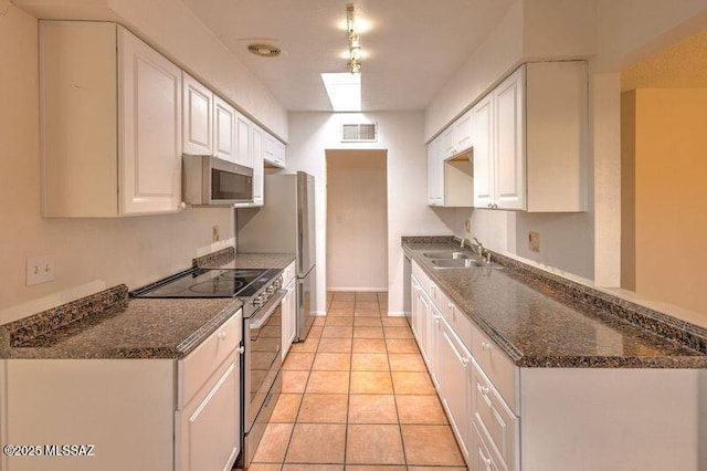 kitchen featuring appliances with stainless steel finishes, sink, light tile patterned floors, and white cabinets