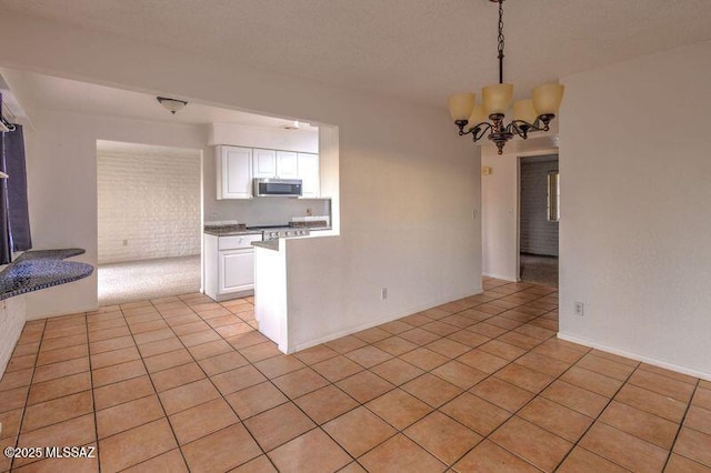 kitchen featuring pendant lighting, a notable chandelier, light tile patterned floors, and white cabinets