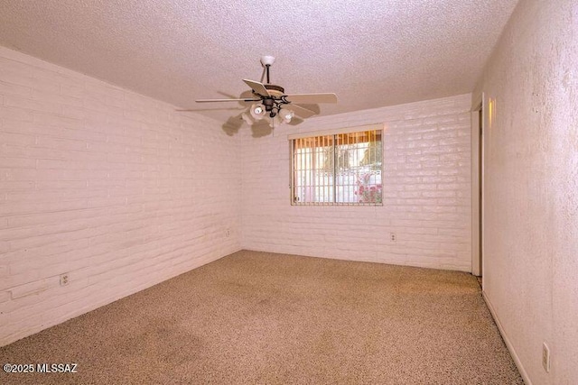 unfurnished room with ceiling fan, brick wall, carpet, and a textured ceiling