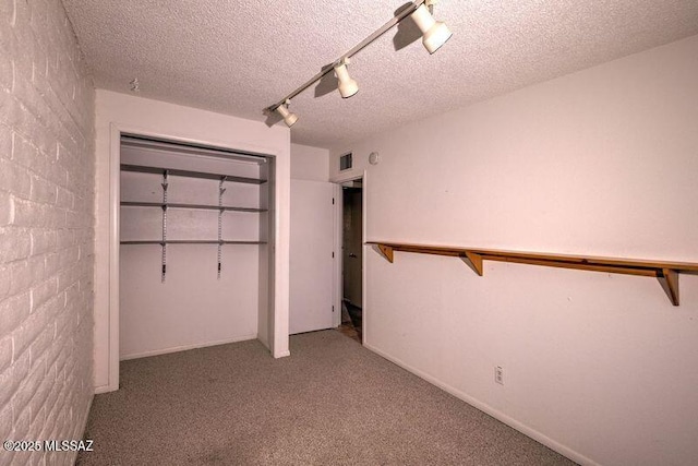 unfurnished bedroom featuring track lighting, carpet floors, a closet, and a textured ceiling