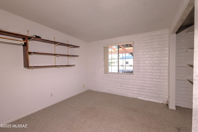 carpeted spare room with brick wall and a textured ceiling