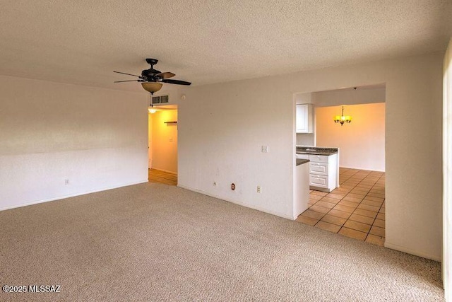 unfurnished living room featuring light carpet, ceiling fan with notable chandelier, and a textured ceiling