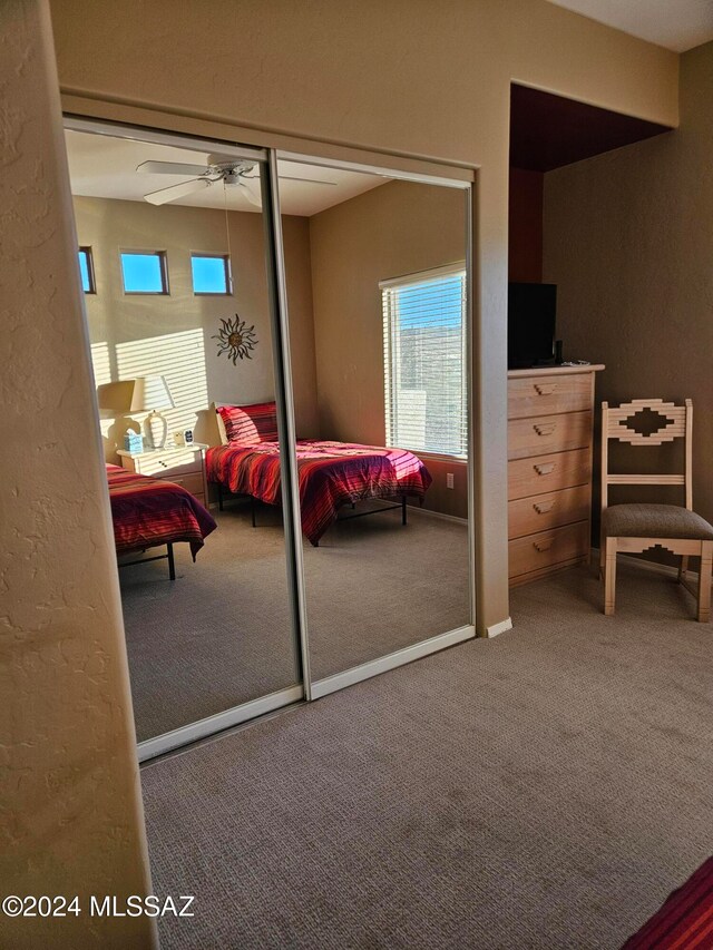 carpeted bedroom with ceiling fan and a closet