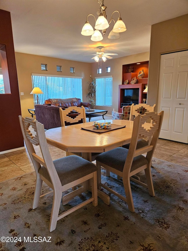 tiled dining room with ceiling fan with notable chandelier