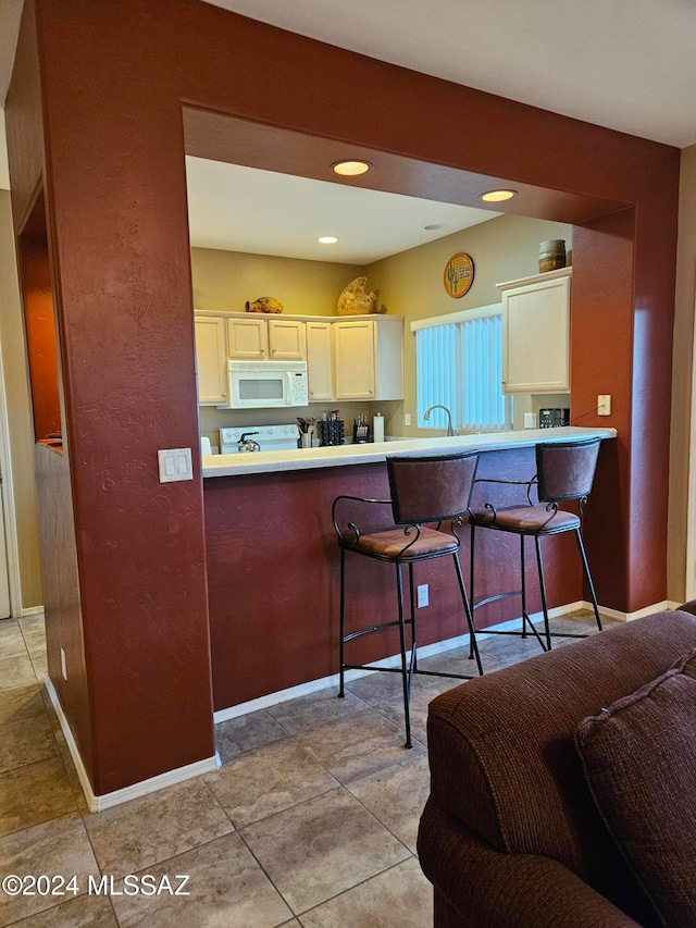 kitchen featuring a breakfast bar area, kitchen peninsula, and light tile patterned floors