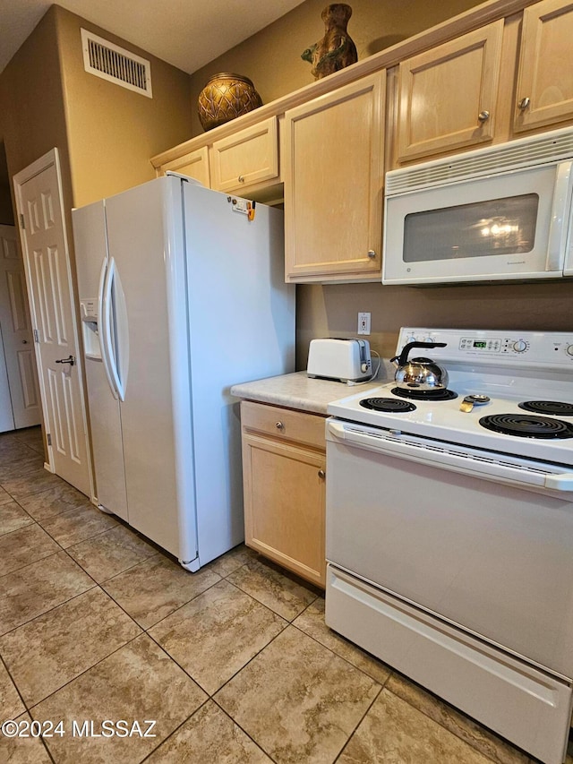 kitchen featuring light brown cabinetry, light tile patterned floors, and white appliances