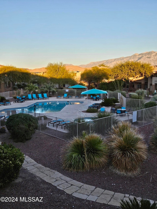 pool at dusk with a mountain view and a patio area