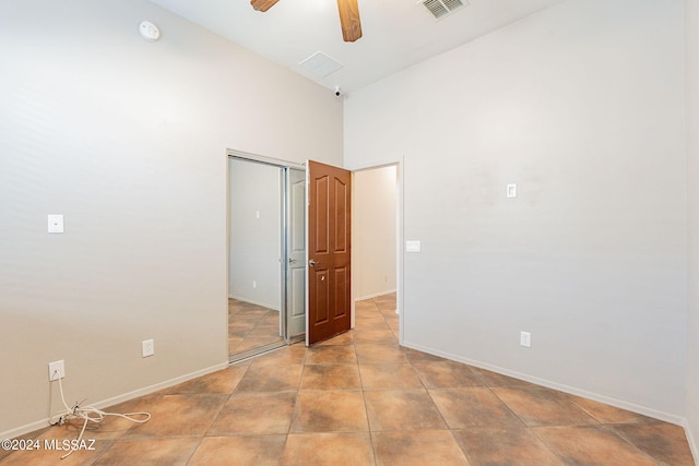 unfurnished bedroom featuring ceiling fan, a closet, high vaulted ceiling, and light tile patterned floors