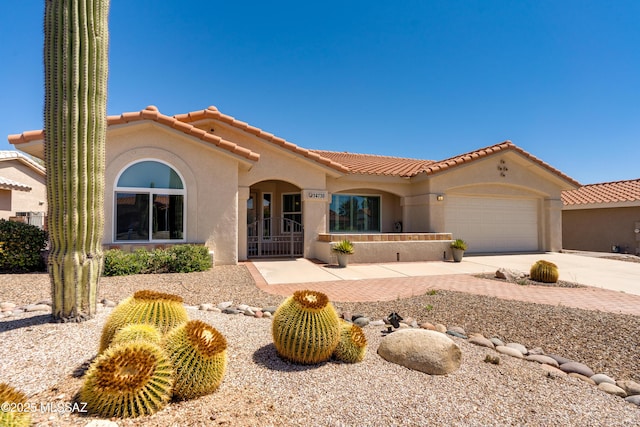 mediterranean / spanish-style house featuring stucco siding, a tiled roof, a garage, and concrete driveway