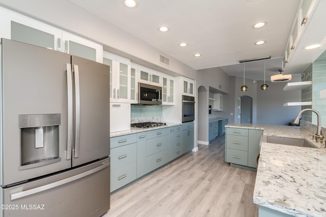 kitchen featuring white cabinets, visible vents, appliances with stainless steel finishes, arched walkways, and a sink