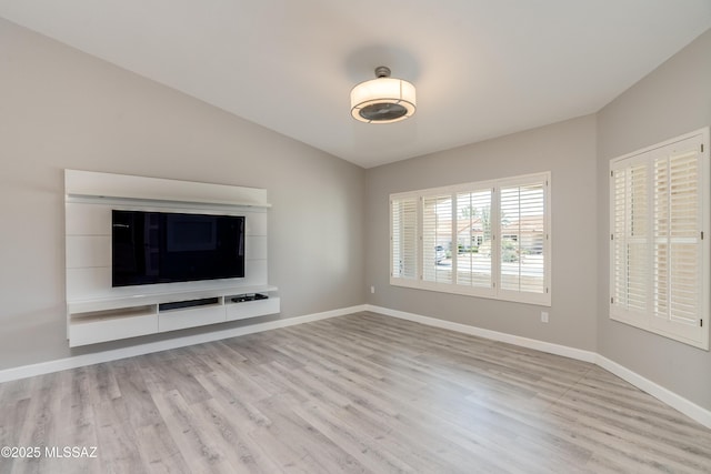 unfurnished living room featuring baseboards, lofted ceiling, and light wood-style floors