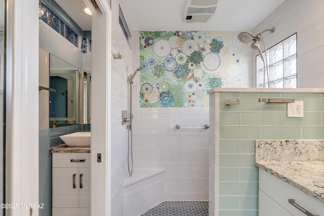 bathroom featuring vanity, tiled shower, tile walls, and visible vents