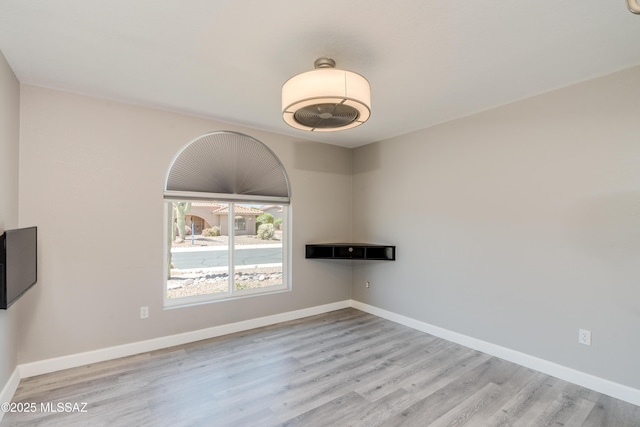 spare room with baseboards and wood finished floors