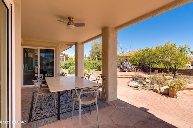 view of patio with outdoor dining area, fence, and ceiling fan