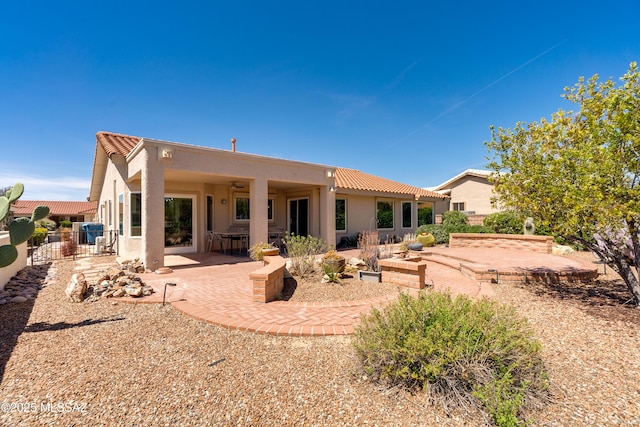 rear view of house featuring fence, a tiled roof, ceiling fan, stucco siding, and a patio area