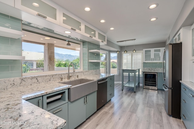 kitchen with light wood-style flooring, wine cooler, stainless steel appliances, a sink, and backsplash