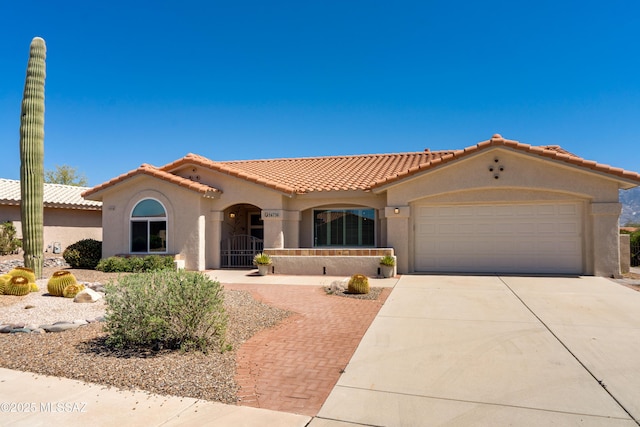 mediterranean / spanish home featuring a tile roof, a garage, driveway, and stucco siding