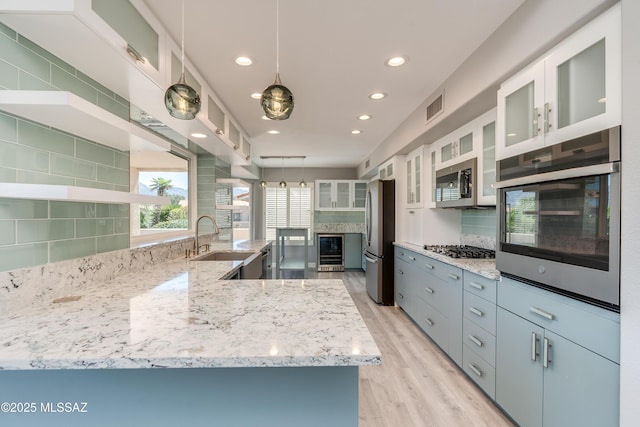 kitchen with backsplash, a sink, beverage cooler, visible vents, and appliances with stainless steel finishes