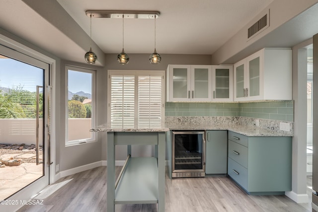 kitchen featuring backsplash, light wood-style flooring, visible vents, and beverage cooler