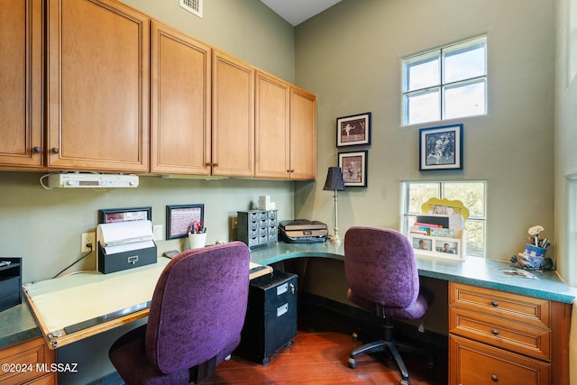 office space with built in desk, dark hardwood / wood-style floors, and a healthy amount of sunlight