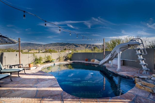 view of swimming pool featuring a patio area, a mountain view, and a water slide