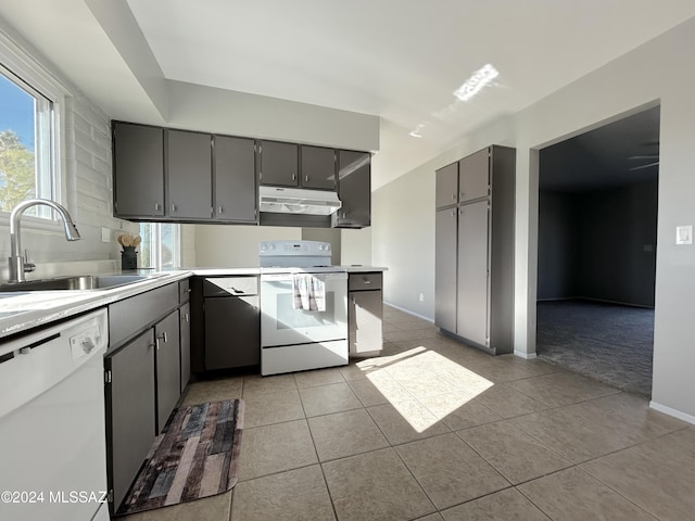 kitchen with light tile patterned flooring, white appliances, gray cabinetry, and sink