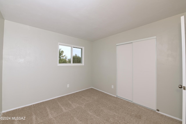 unfurnished bedroom with light carpet and a closet