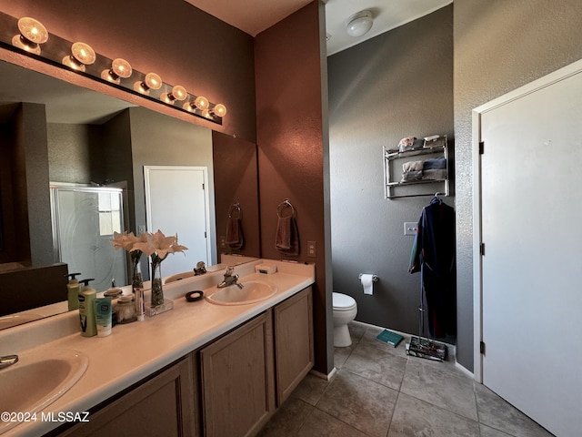 bathroom with toilet, vanity, a shower with door, and tile patterned flooring