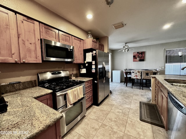 kitchen with sink, ceiling fan, appliances with stainless steel finishes, light stone countertops, and light tile patterned flooring