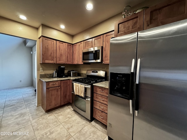 kitchen with stainless steel appliances, light tile patterned floors, and light stone counters