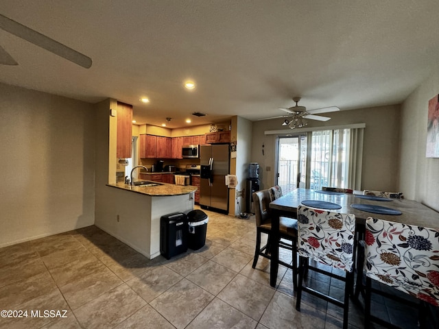 kitchen featuring light tile patterned flooring, appliances with stainless steel finishes, sink, ceiling fan, and kitchen peninsula