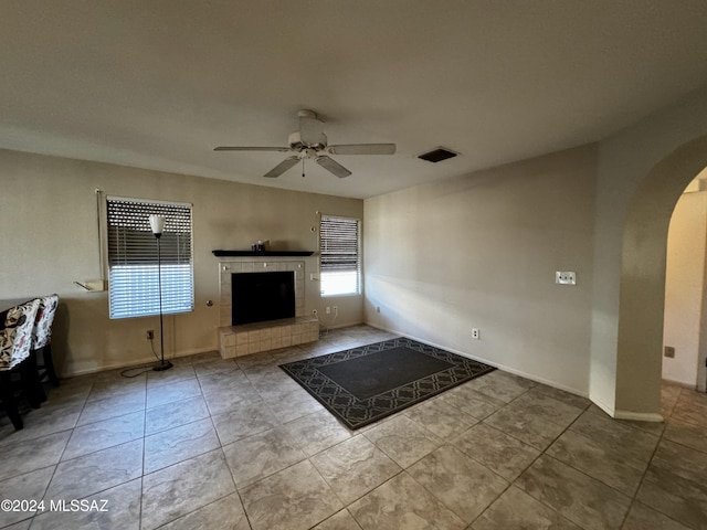 unfurnished living room featuring a tile fireplace, light tile patterned flooring, and ceiling fan