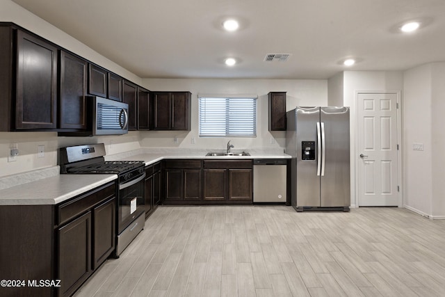 kitchen with dark brown cabinets, sink, appliances with stainless steel finishes, and light hardwood / wood-style flooring