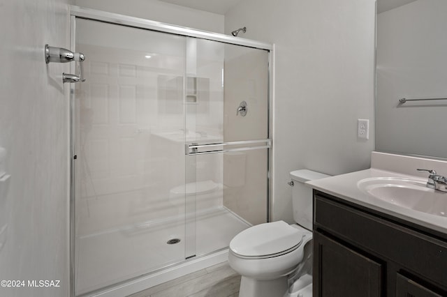 bathroom featuring vanity, toilet, a shower with door, and wood-type flooring