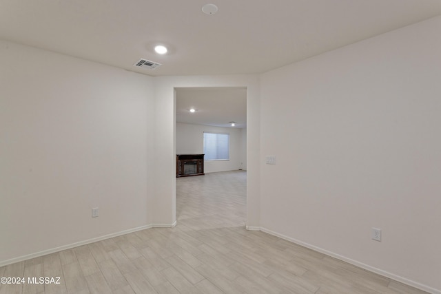 empty room with a fireplace and light hardwood / wood-style flooring