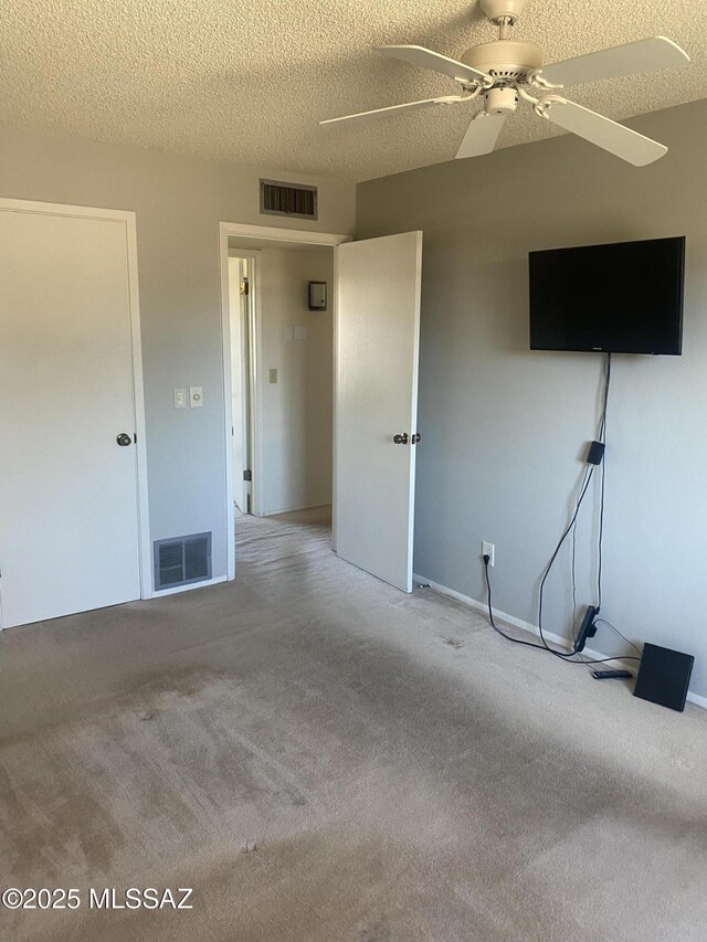 unfurnished bedroom with carpet, visible vents, ceiling fan, and a textured ceiling