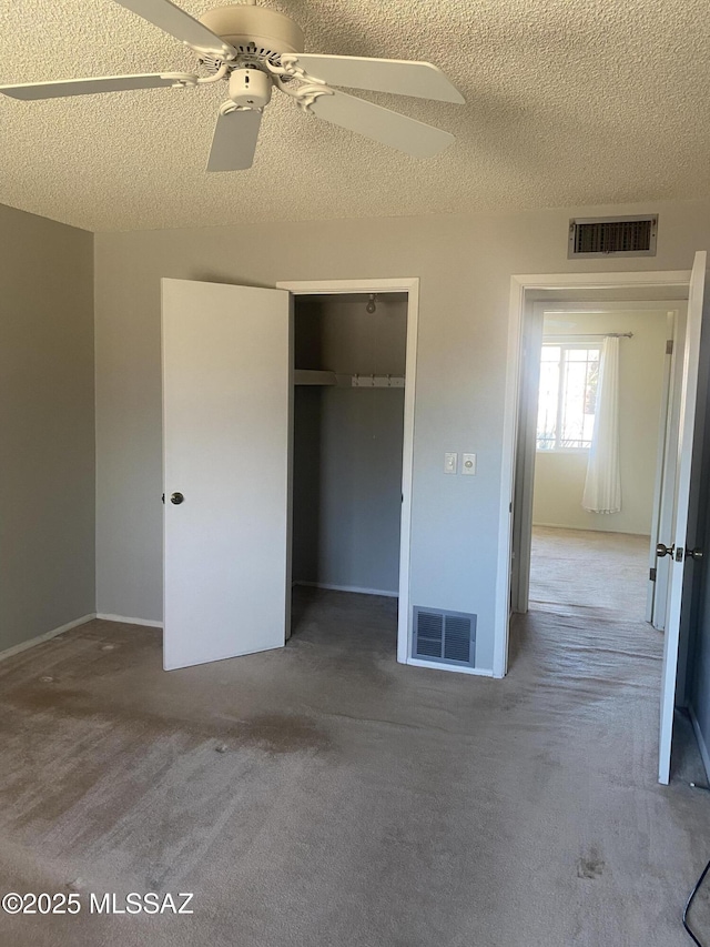 unfurnished bedroom featuring a closet, visible vents, a textured ceiling, and carpet flooring