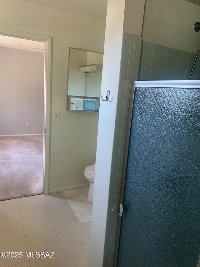 full bathroom featuring tile patterned flooring, baseboards, toilet, and a walk in shower