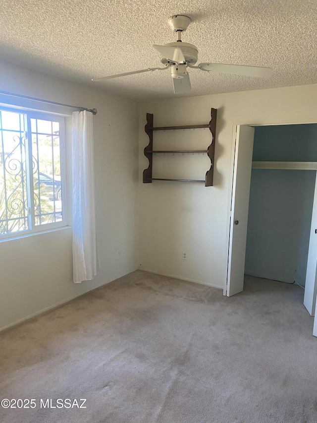 unfurnished bedroom featuring light colored carpet, ceiling fan, and a textured ceiling