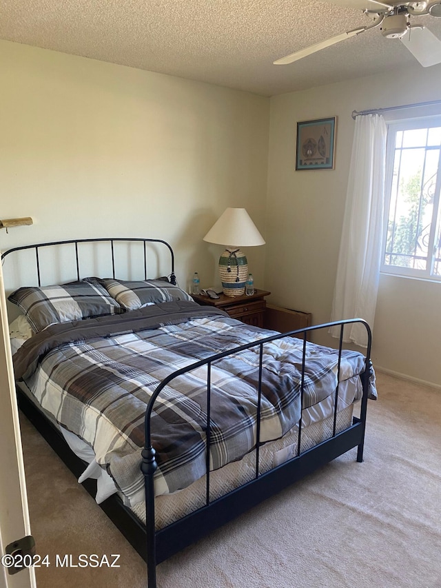 carpeted bedroom featuring ceiling fan and a textured ceiling